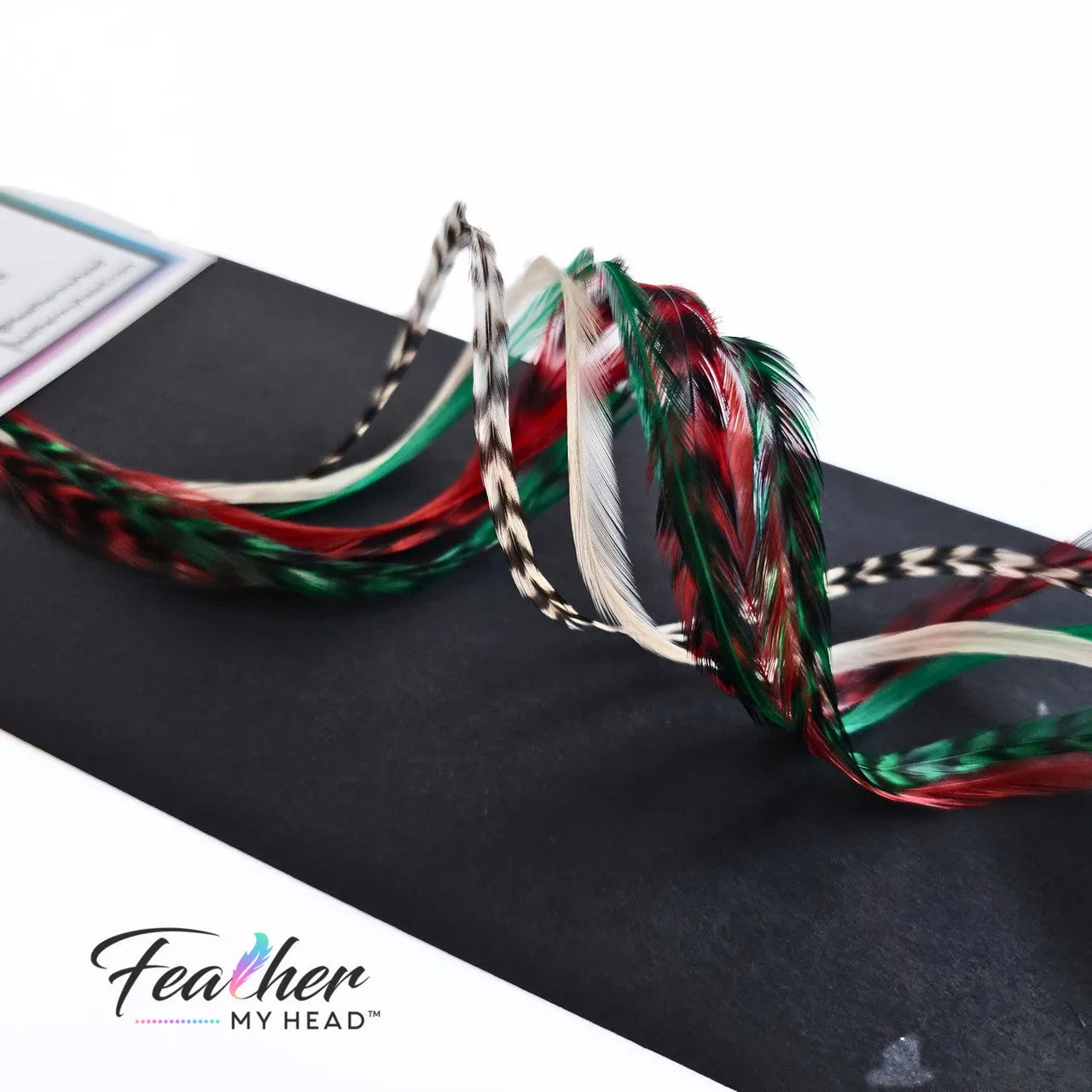 Dive into the holiday fun with our Elfin Around Christmas Collection of feather extensions! This 6-piece pack of hair feather extensions brings a playful touch to your look. With vibrant red, green, classic white, and natural black and white grizzly hair feathers, Elfin Around adds a festive twist to your hair. Get ready to embrace the holiday spirit and Elf Around in style!
