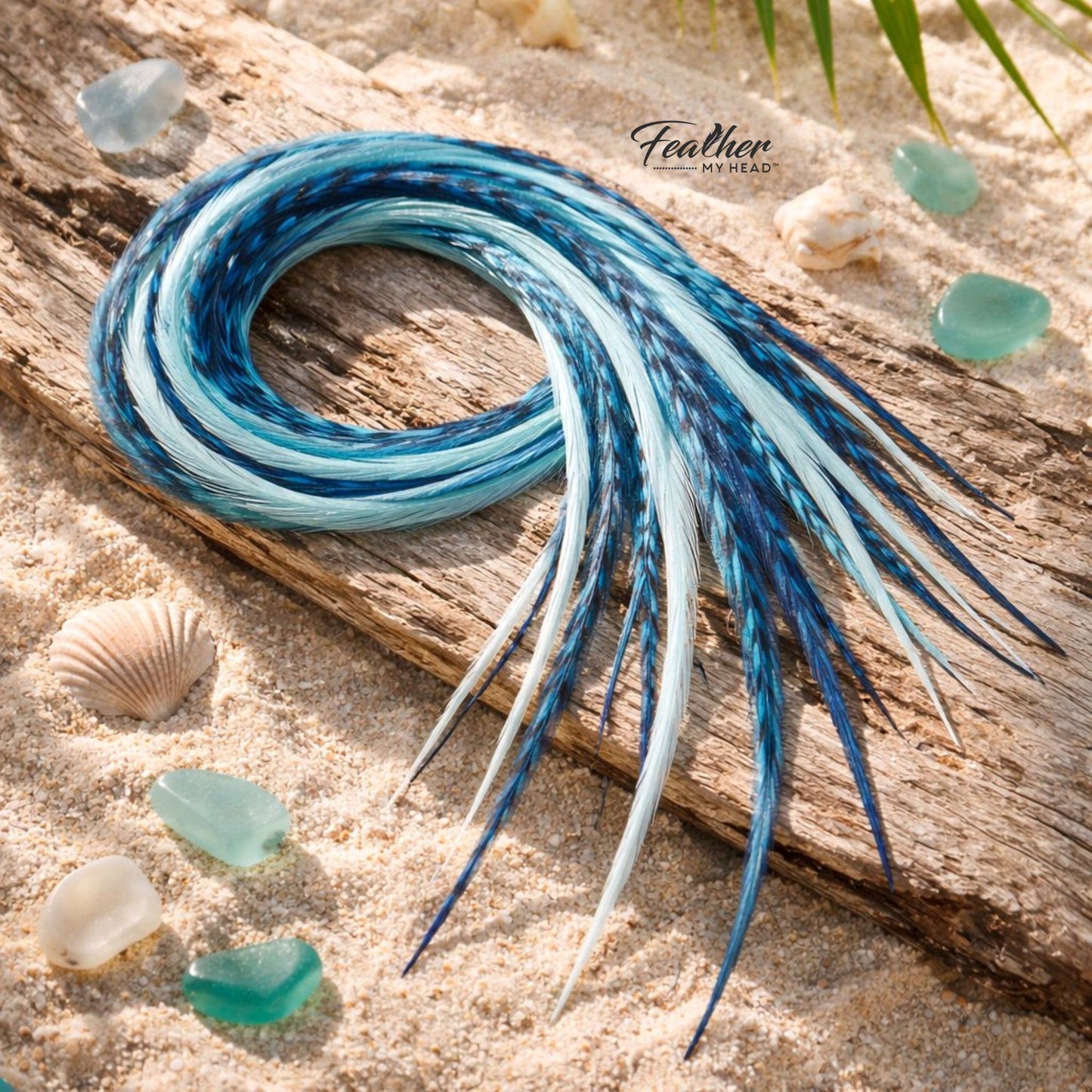 Sea Glass feather hair extensions styled on driftwood with blue, aqua, and seafoam coastal tones